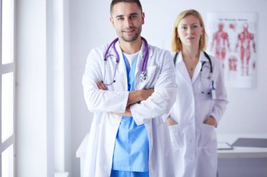 Yakışıklı doktor genç bayan hastasıyla konuşuyor ve ofisinde otururken notlar alıyor.