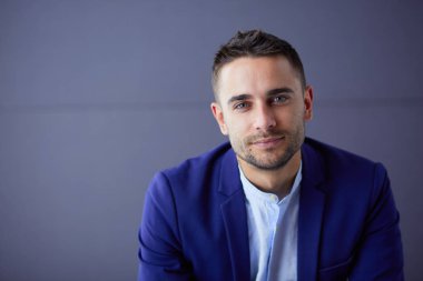 Gri arka planda yalnız oturan genç iş adamı