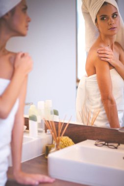 Banyo aynası önünde duran genç çekici kadın