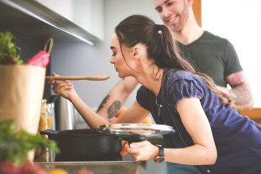 Bir çift evdeki mutfaklarında birlikte yemek pişiriyor.