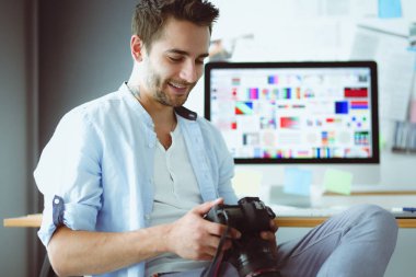 İnternette çalışırken bilgisayarın ve dizüstü bilgisayarın önünde grafik stüdyosunda oturan genç tasarımcının portresi.