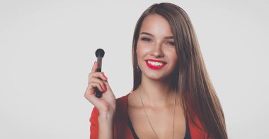 Genç güzel kadın elinde makyaj için fırça tutar