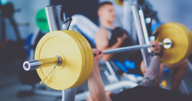 Genç adam eğitmen ile spor salonunda halter kaldırma