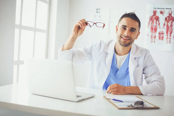 Portrait d'un médecin avec un ordinateur portable assis au bureau médical — Photo