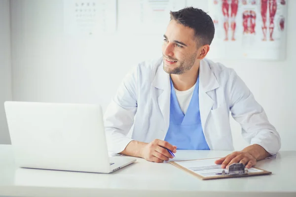 Retrato de un médico varón con portátil sentado en el escritorio en el consultorio médico — Foto de Stock