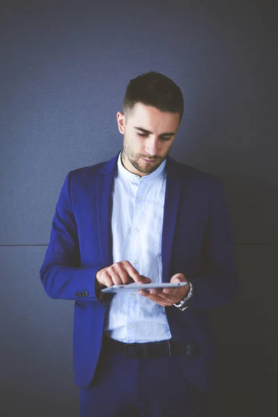 Young businessman sitting isolated on grey background — Stock Photo, Image