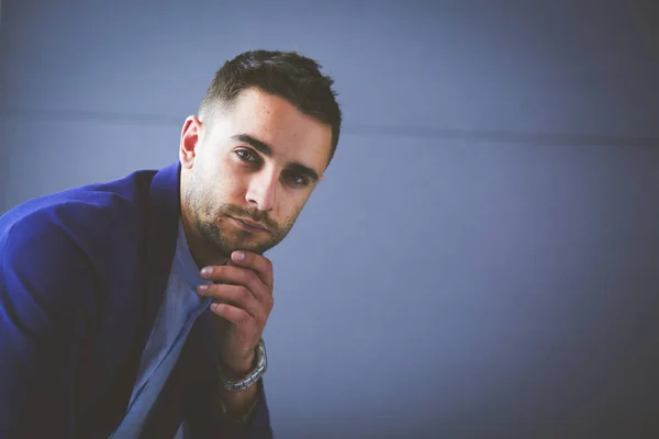 Young businessman sitting isolated on grey background — Stock Photo, Image