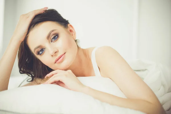 Piękna młoda kobieta leżąca na białym łóżku — Zdjęcie stockowe