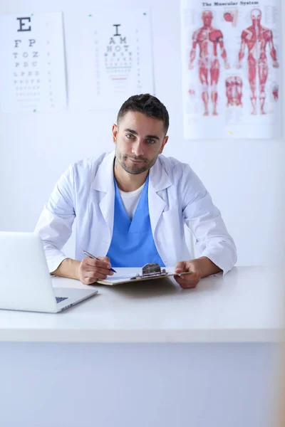 Porträt eines männlichen Arztes mit Laptop am Schreibtisch in der Arztpraxis — Stockfoto