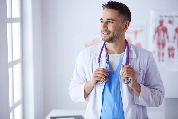 Retrato médico masculino joven y confiado de pie en el consultorio médico — Foto de Stock