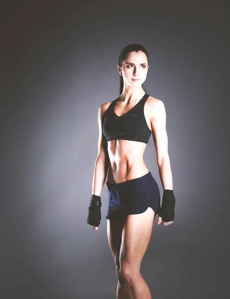 Musclé jeune femme posant en vêtements de sport sur fond noir . — Photo