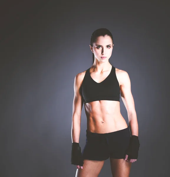 Muscular young woman posing in sportswear against black background. — Stock Photo, Image