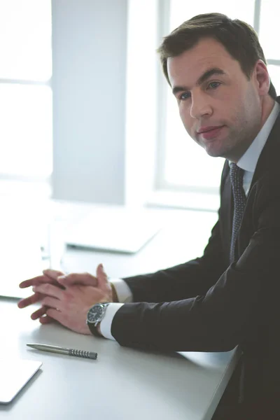 Porträt eines jungen Mannes, der an seinem Schreibtisch im Büro sitzt. — Stockfoto