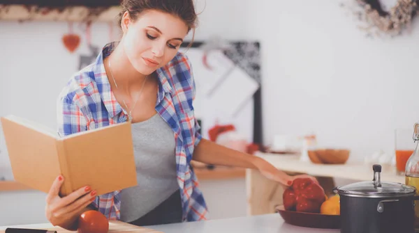 Mujer joven leyendo libro de cocina en la cocina, buscando receta —  Fotos de Stock