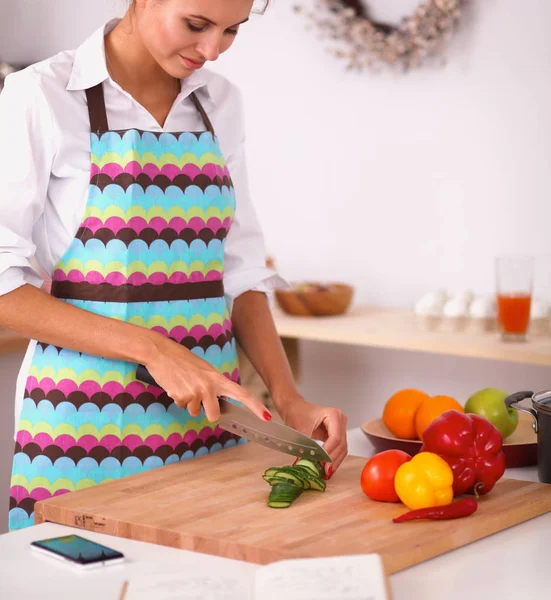 Leende kvinna tillagar sallad i köket — Stockfoto