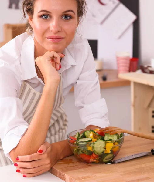 Mujer joven comiendo ensalada fresca en la cocina moderna — Foto de Stock