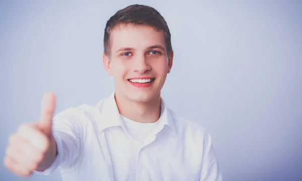 Retrato de jovem sorrindo sentado em fundo cinza — Fotografia de Stock