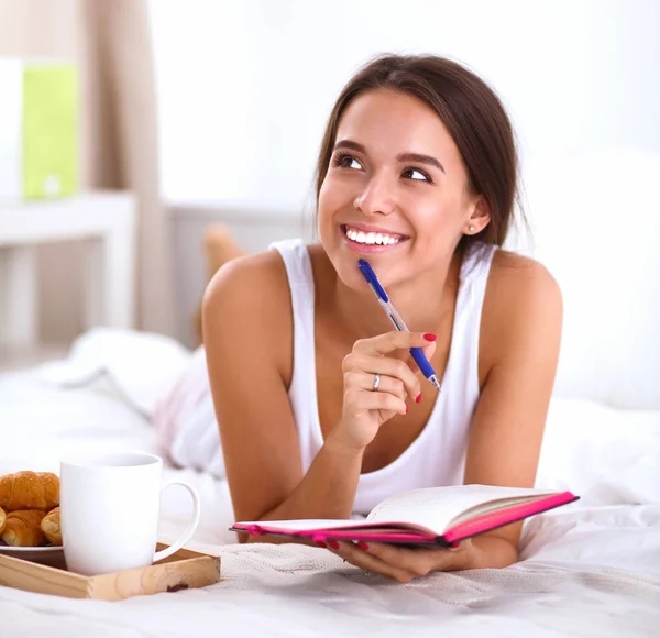 Joven hermosa mujer acostada en la cama escribiendo un diario — Foto de Stock