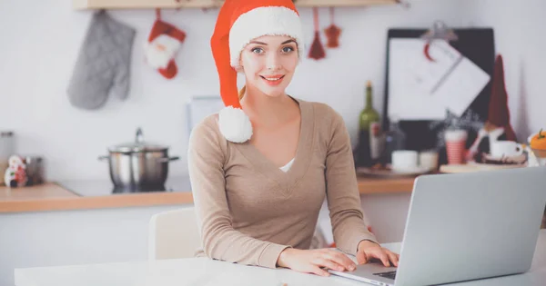 Glimlachende jonge vrouw in de keuken, geïsoleerd op kerst achtergrond — Stockfoto