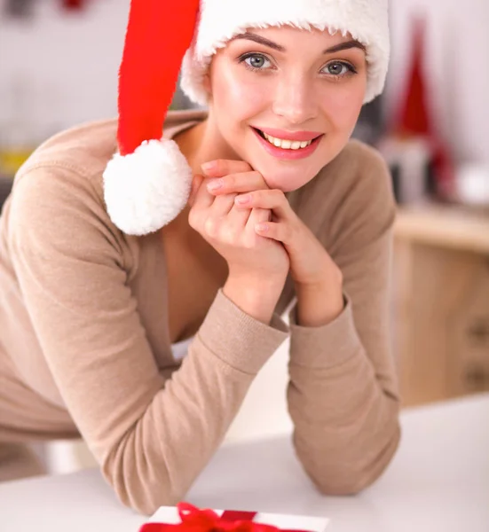 Lächelnde junge Frau in der Küche, isoliert auf weihnachtlichem Hintergrund — Stockfoto