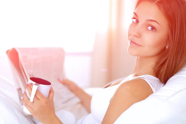 A pretty young woman sitting in bed under cover — Stock Photo, Image