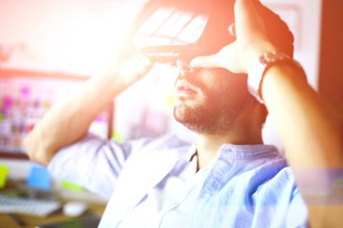 Genç erkek yazılım programcısı ofiste üç boyutlu sanal gerçeklik gözlükleriyle yeni bir uygulama test ediyor.