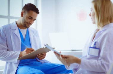 Genç ve kendinden emin doktorların portresi tıp ofisinde duruyor.