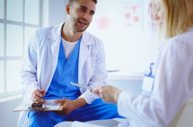 Genç ve kendinden emin doktorların portresi tıp ofisinde duruyor.
