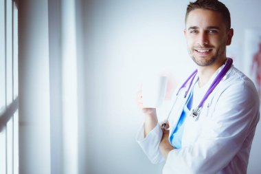 Elinde kahve fincanı olan genç bir doktor.