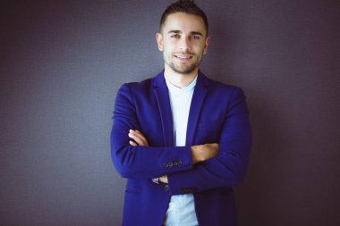 Gri arka planda tek başına duran genç iş adamı