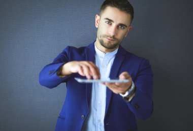 Mutlu genç adam gri arka plan üzerinde izole dijital tablet kullanma