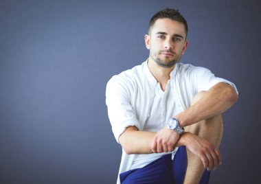 Gri arka planda yalnız oturan genç iş adamı