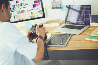 İnternette çalışırken bilgisayarın ve dizüstü bilgisayarın önünde grafik stüdyosunda oturan genç tasarımcının portresi