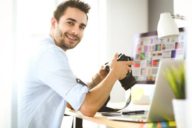 İnternette çalışırken bilgisayarın ve dizüstü bilgisayarın önünde grafik stüdyosunda oturan genç tasarımcının portresi