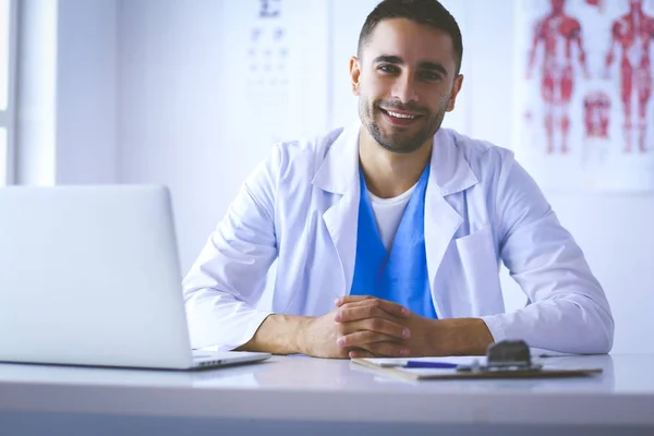 Retrato de un médico varón con portátil sentado en el escritorio en el consultorio médico — Foto de Stock
