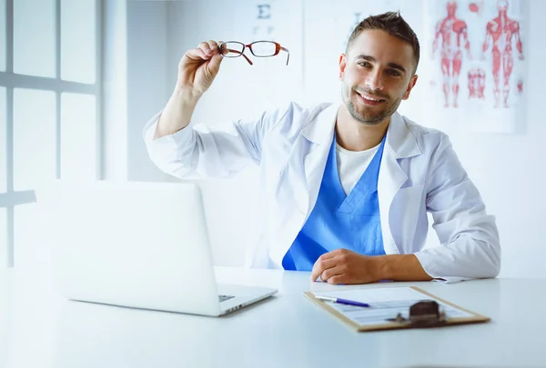 Porträt eines männlichen Arztes mit Laptop am Schreibtisch in der Arztpraxis — Stockfoto