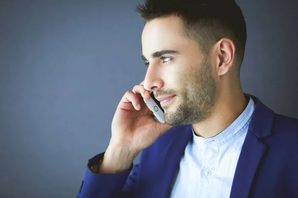 Attractive young man with smartphone on color background