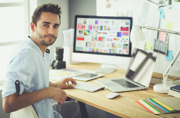 Porträt eines jungen Designers, der im Grafikstudio vor Laptop und Computer sitzt, während er online arbeitet — Stockfoto