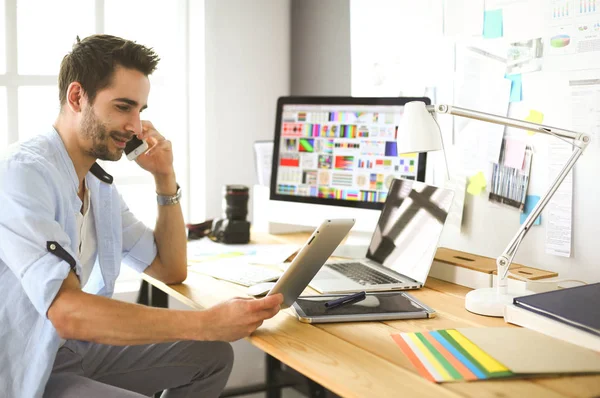 Porträt eines jungen Designers, der im Grafikstudio vor Laptop und Computer sitzt, während er online arbeitet — Stockfoto