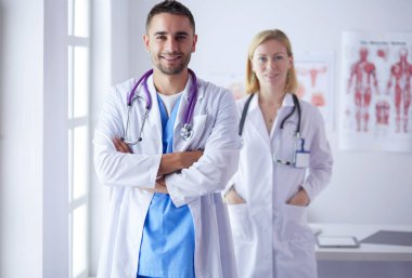 Genç ve kendinden emin doktorların portresi tıp ofisinde duruyor.