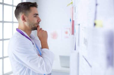 Genç ve kendinden emin erkek doktor portresi tıp ofisinde duruyor.