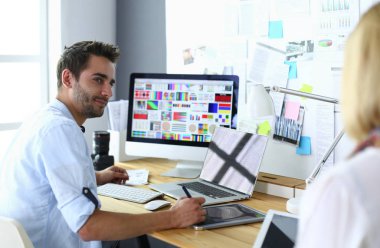 İnternette çalışırken bilgisayarın ve dizüstü bilgisayarın önünde grafik stüdyosunda oturan genç tasarımcının portresi