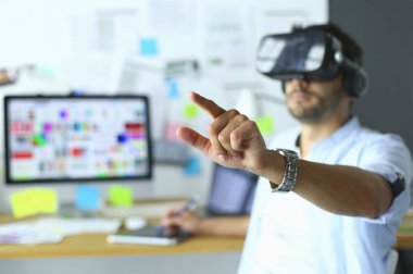 Genç erkek yazılım programcısı ofiste üç boyutlu sanal gerçeklik gözlükleriyle yeni bir uygulama test ediyor.