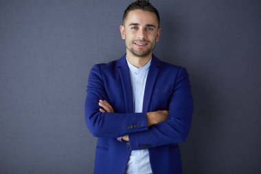 Gri arka planda tek başına duran genç iş adamı