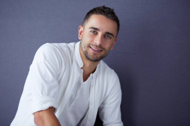 Gri arka planda yalnız oturan genç iş adamı