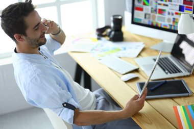İnternette çalışırken bilgisayarın ve dizüstü bilgisayarın önünde grafik stüdyosunda oturan genç tasarımcının portresi