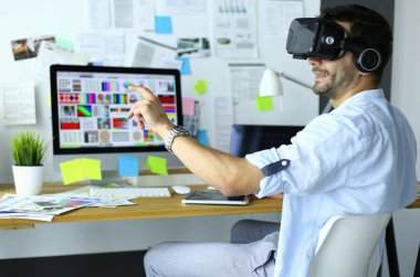 Genç erkek yazılım programcısı ofiste üç boyutlu sanal gerçeklik gözlükleriyle yeni bir uygulama test ediyor.