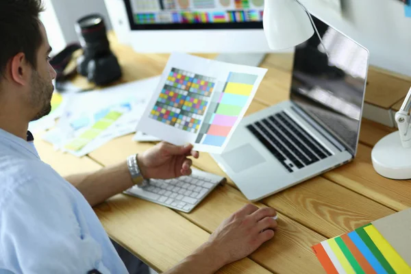 Porträt eines jungen Designers, der im Grafikstudio vor Laptop und Computer sitzt, während er online arbeitet — Stockfoto