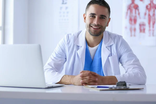 Portrait d'un médecin avec un ordinateur portable assis au bureau médical — Photo