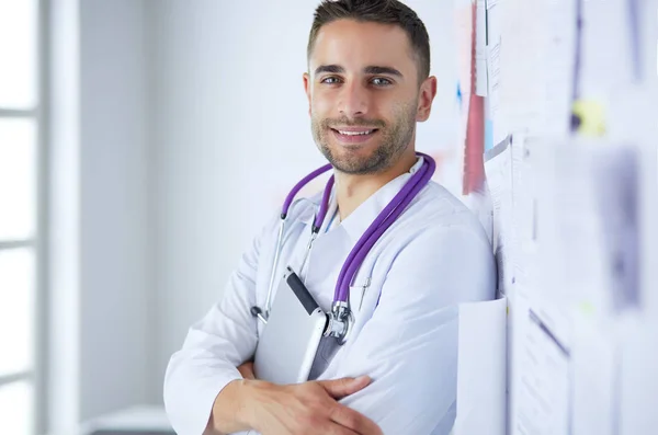 Jonge en zelfverzekerde mannelijke arts portret staan in medisch kantoor — Stockfoto